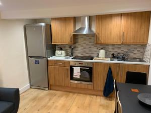 uma cozinha com armários de madeira e um frigorífico de aço inoxidável em The Inverleither em Edimburgo