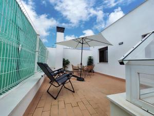 un patio con sillas y una sombrilla en el balcón en La Terraza de Lulú Little Apartments en Cádiz