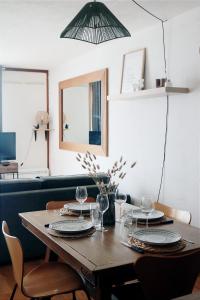a dining room table with plates and wine glasses at Charmant Appartement Les temples du Soleil in Font-Romeu-Odeillo-Via