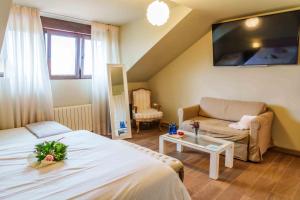 Habitación de hotel con cama y sofá en Hospedaje Villa Pilar en Santillana del Mar