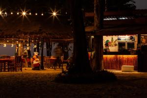 a person sitting in front of a restaurant at night at Eco Lanta Hideaway Beach Resort in Ko Lanta