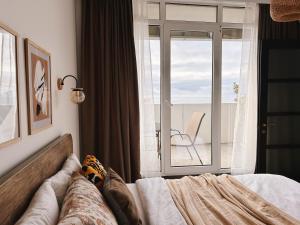 1 dormitorio con 1 cama y ventana con silla en Seaside Apartment en Batumi