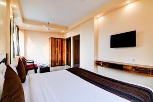 Eco Corporate Inn 2 Rajarhat في kolkata: غرفة فندقية بسرير وتلفزيون بشاشة مسطحة