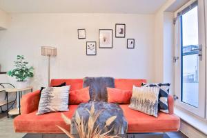 a living room with an orange couch with pillows at StayRight Whitchurch Place: 2-bed Flat in Cardiff in Cardiff