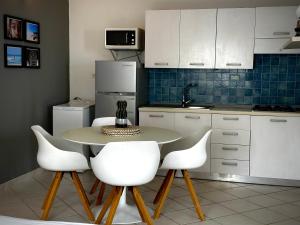 uma cozinha com uma mesa e quatro cadeiras brancas em Wind - Apartments close to the beach em Santa Maria