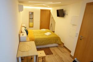 a small bedroom with a yellow bed and a table at CASA ORIGENS ll in Seia