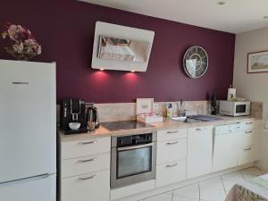cocina con armarios blancos y pared púrpura en B&B La Rive - Le Mont Saint Michel, en Ardevon