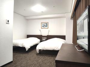 a hotel room with two beds and a flat screen tv at Hotel Alpha-One Yatsushiro in Yatsushiro