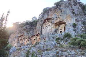 a rocky mountain with ancient buildings on it at King Tombs Suit in Mugla