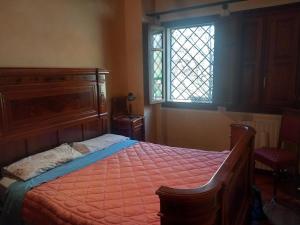 a bedroom with a bed with an orange comforter and a window at Appartamento Simone in Fanano