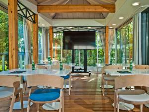 a dining room with tables and chairs and a flat screen tv at Rosevia Resort & Spa in Jastrzębia Góra