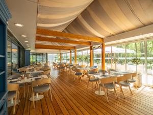 un comedor con mesas, sillas y ventanas en Rosevia Resort & Spa, en Jastrzębia Góra