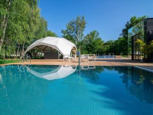a swimming pool with a tent next to a building at Rosevia Resort & Spa in Jastrzębia Góra