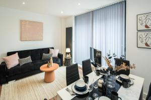 a living room with a black couch and a table at BethnalGreen Apartments by Sleepy in London