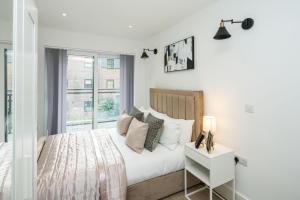a white bedroom with a bed and a window at BethnalGreen Apartments by Sleepy in London