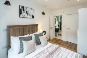 - une chambre avec un grand lit blanc et des oreillers dans l'établissement BethnalGreen Apartments by Sleepy, à Londres