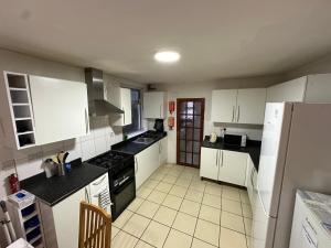 a kitchen with white cabinets and black appliances at Stratford Guesthouse in London