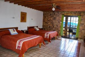 a bedroom with two beds and a stone wall at Hotel Divisadero Barrancas in El Divisadero