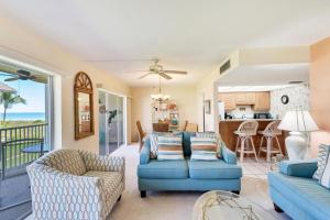 uma sala de estar com um sofá azul e cadeiras em Sanibel Siesta on the Beach unit 501 condo em Sanibel