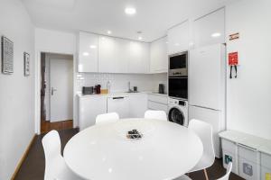 biała kuchnia z białym stołem i krzesłami w obiekcie Urban Tech Retreat: Modern Hubs for Remote Living w Lizbonie