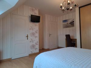 1 dormitorio con 1 cama y TV en la pared en B&B La Rive - Le Mont Saint Michel en Ardevon