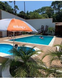 CASA TO Patrao LUXO في إتابيسيريكا دا سيرا: وجود مظلة برتقالية بجانب المسبح مع وجود شخص في الماء