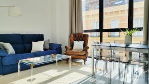 a living room with a blue couch and a glass table at Living4malaga Victoria Center Apartment in Málaga