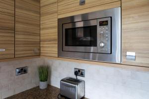 a microwave oven on a wall in a kitchen at Exquisite 3 Bedroom Home Central Birmingham in Birmingham