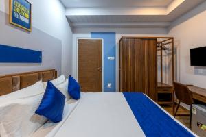 a bedroom with a bed with blue pillows and a desk at Smart Stay by Luxe Gachibowli in Hyderabad