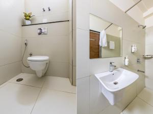 a white bathroom with a toilet and a sink at Smart Stay by Luxe Gachibowli in Hyderabad