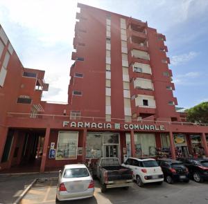 un bâtiment rouge avec des voitures garées dans un parking dans l'établissement Appartamento Fiore, à Follonica