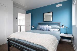 伊斯特曼的住宿－Cottage 2 de la Chute，一间蓝色的卧室,配有一张大床和镜子