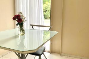 einen Glastisch mit einer Vase aus Blumen und einem Stuhl in der Unterkunft 100m da Rodoviaria, 600m da UFV, Ar Condicionado, Elevador e Garagem Paga in Viçosa + 1 Foto