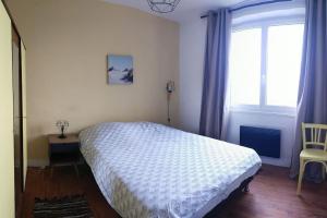 ein Schlafzimmer mit einem Bett, einem Fenster und einem Stuhl in der Unterkunft Maison de location Pengourven in Plouguerneau