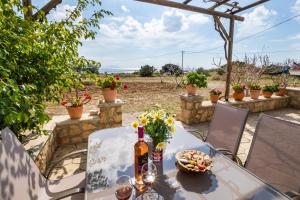 - une table avec une bouteille de vin et des fleurs sur la terrasse dans l'établissement Venetia's Garden, à Lefkos Karpathou