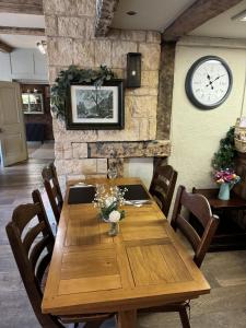 een houten tafel in een kamer met een klok aan de muur bij The White Lion Hotel in Upton upon Severn
