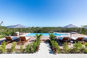 a resort with a pool and chairs and umbrellas at Onyx I Long Bay Retreat I Luxury Stay Near Grace Bay & Long Bay Beach in Long Bay Hills +7 photos