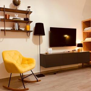 a living room with a yellow chair and a television at Muralta Suite & Luxury Rooms in Altamura