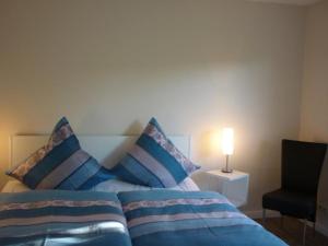 a bedroom with a blue bed with pillows and a lamp at Ferienwohnung am Pfarrhof in Ziethen