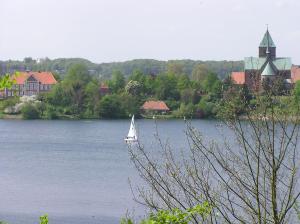 un velero en el agua frente a una ciudad en Ferienwohnung am Pfarrhof, en Ziethen