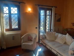 sala de estar con sofá, silla y ventanas en Appartamento Simone en Fanano