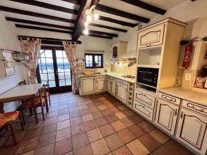 Salerm的住宿－Le Petit Manoir de Campagne，一间大厨房,配有白色橱柜、一张桌子和一张桌子