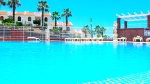 une grande piscine d'eau bleue en face d'un bâtiment dans l'établissement Villas Canarias apartamento 310, à Adeje