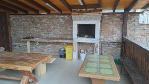 uma cozinha exterior com mesas de madeira e uma parede de tijolos em Casa Irimescu em Gura Humorului