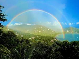 a rainbow over a mountain and a body of water at Windsong Villa - Sleeps 8 Stunning Views in Cruz Bay