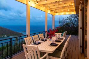 a table on a deck with a view of the ocean at Windsong Villa - Sleeps 8 Stunning Views in Cruz Bay