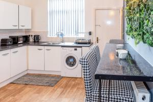 a kitchen with a washing machine and a sink at Stylish 2 bed house 7mins to Manchester City center in Manchester