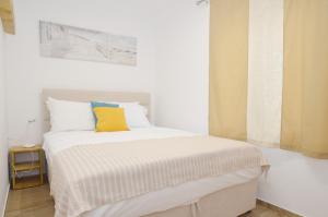 een slaapkamer met een wit bed en een geel kussen bij DC Apartment C in Kotor +22 foto's
