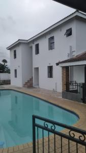 a house with a swimming pool in front of a building at Jnc Lodge in Richards Bay