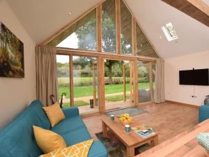 a living room with a blue couch and a large window at Nettlebed Farm Holiday Lets Barn3 in Durley